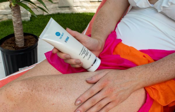 An image of a woman applying Firm Body Contour Cream to her legs.